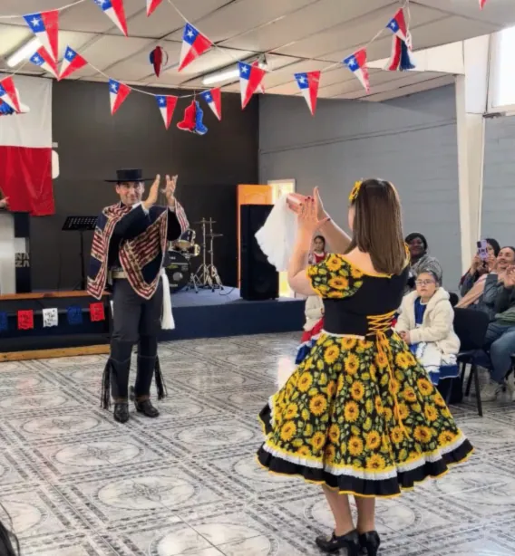 Una pareja baila cueca con trajes típicos en la celebración de Fiestas Patrias de la iglesia.