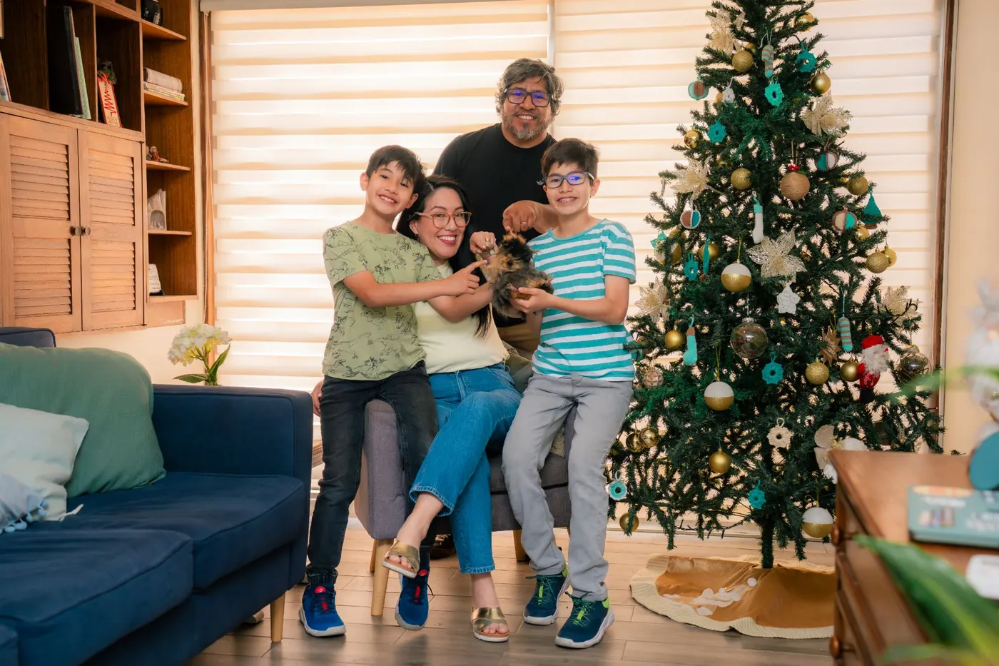 David señala al cuy que sostiene Lucas; Ruth y Mateo ríen sentados en el sillón.